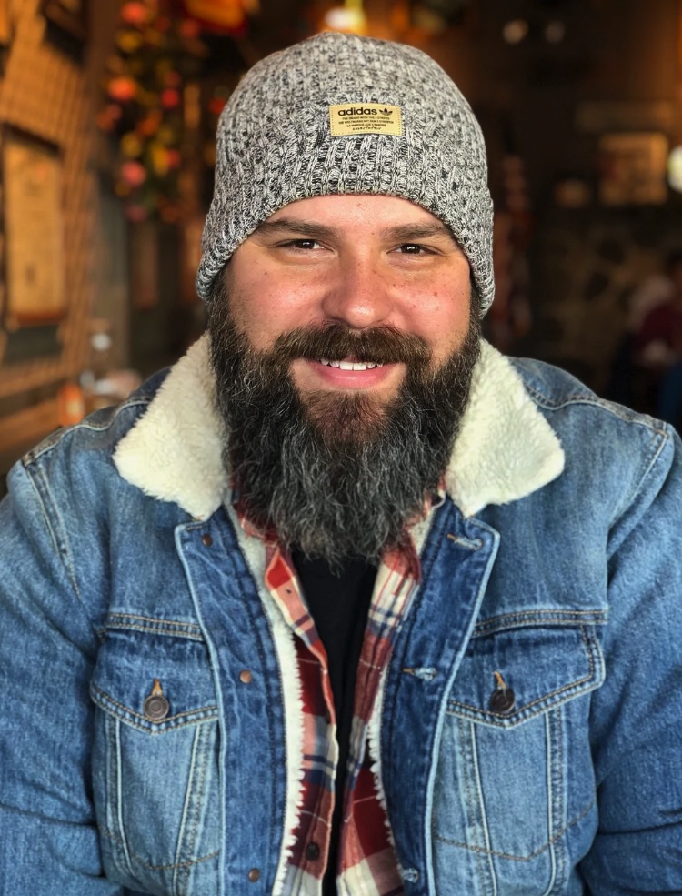 Peter Magulak, smiling, in a grey knit beanie and a denim jacket