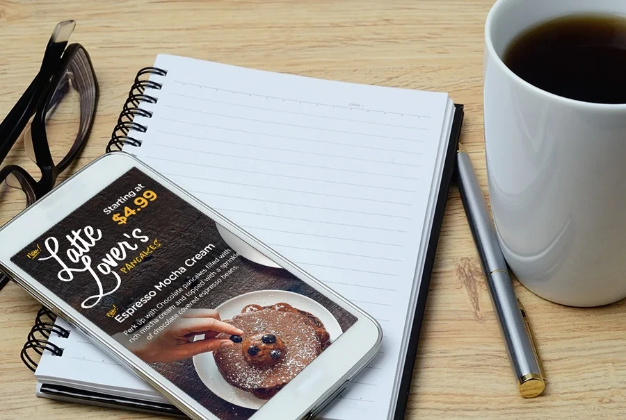Latte Lover's campaign on a phone resting on a notebook beside a cup of coffee