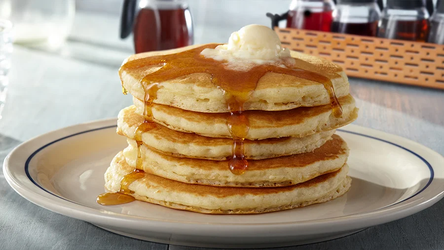 Stack of IHOP original buttermilk pancakes with whipped butter and syrup