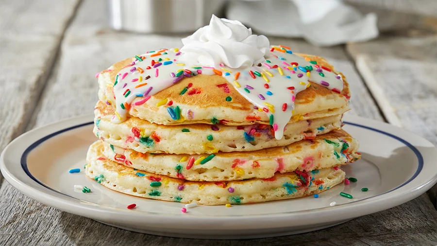 Rainbow-sprinkle cupcake pancakes with icing and whipped cream