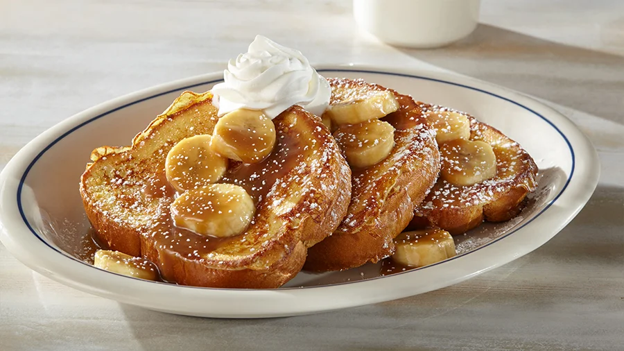 French toast topped with sliced bananas and whipped cream