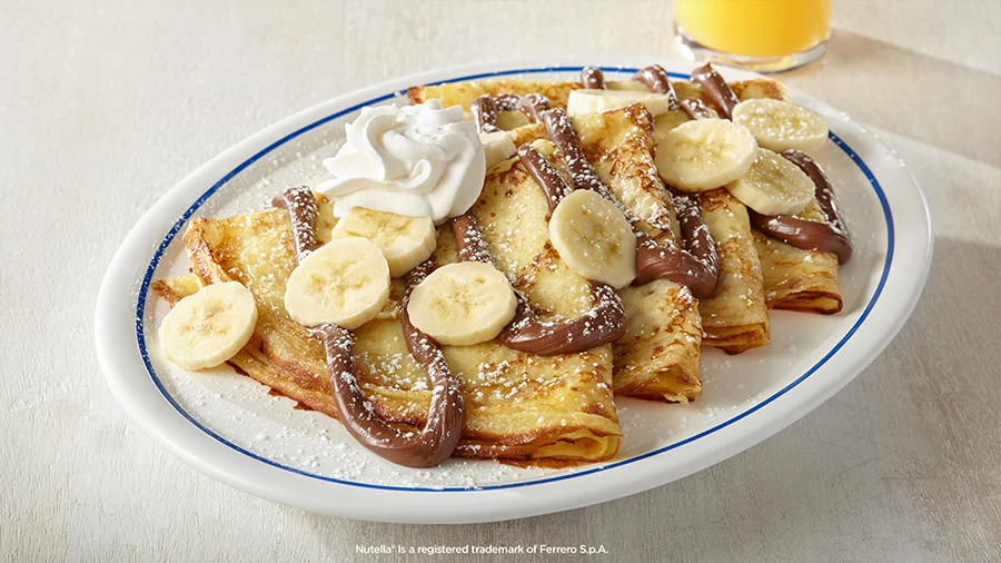 Chocolate-hazelnut crepes topped with sliced bananas and whipped cream