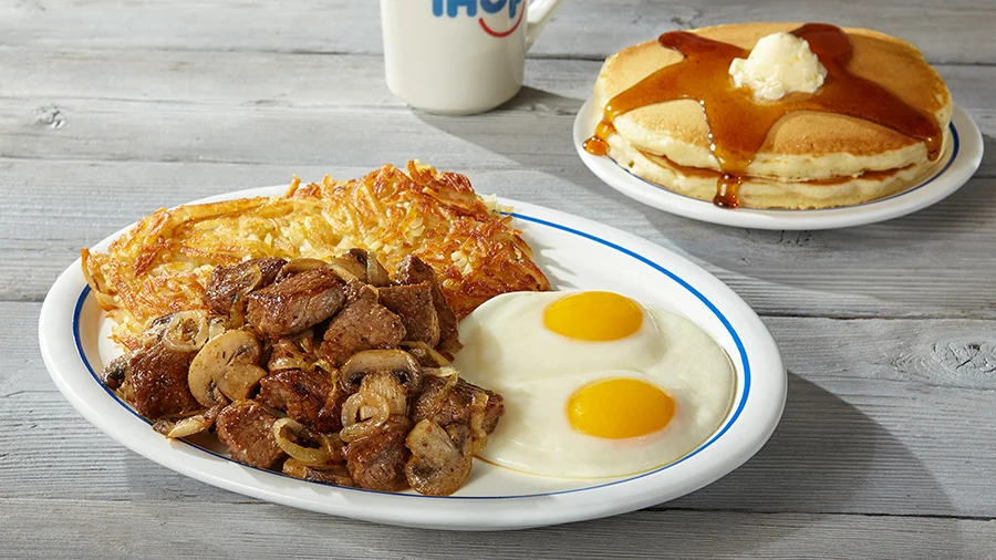 Steak tips with mushrooms, hash browns, eggs and a side of pancakes